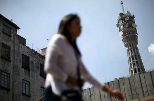 Una mujer camina cerca de una torre de telecomunicaciones en la Ciudad de México