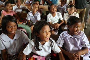 Des élèves souriants sont assis dans une salle de classe à l'école élémentaire de Bislig à Tanauan City, province de Leyte, Philippines.