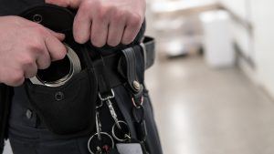 Police officer or security staff takes up handcuffs for arrest of criminal.