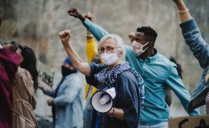 Groupe de militants aux poings levés protestant dans les rues, manifestation de protestation et concept de coronavirus.